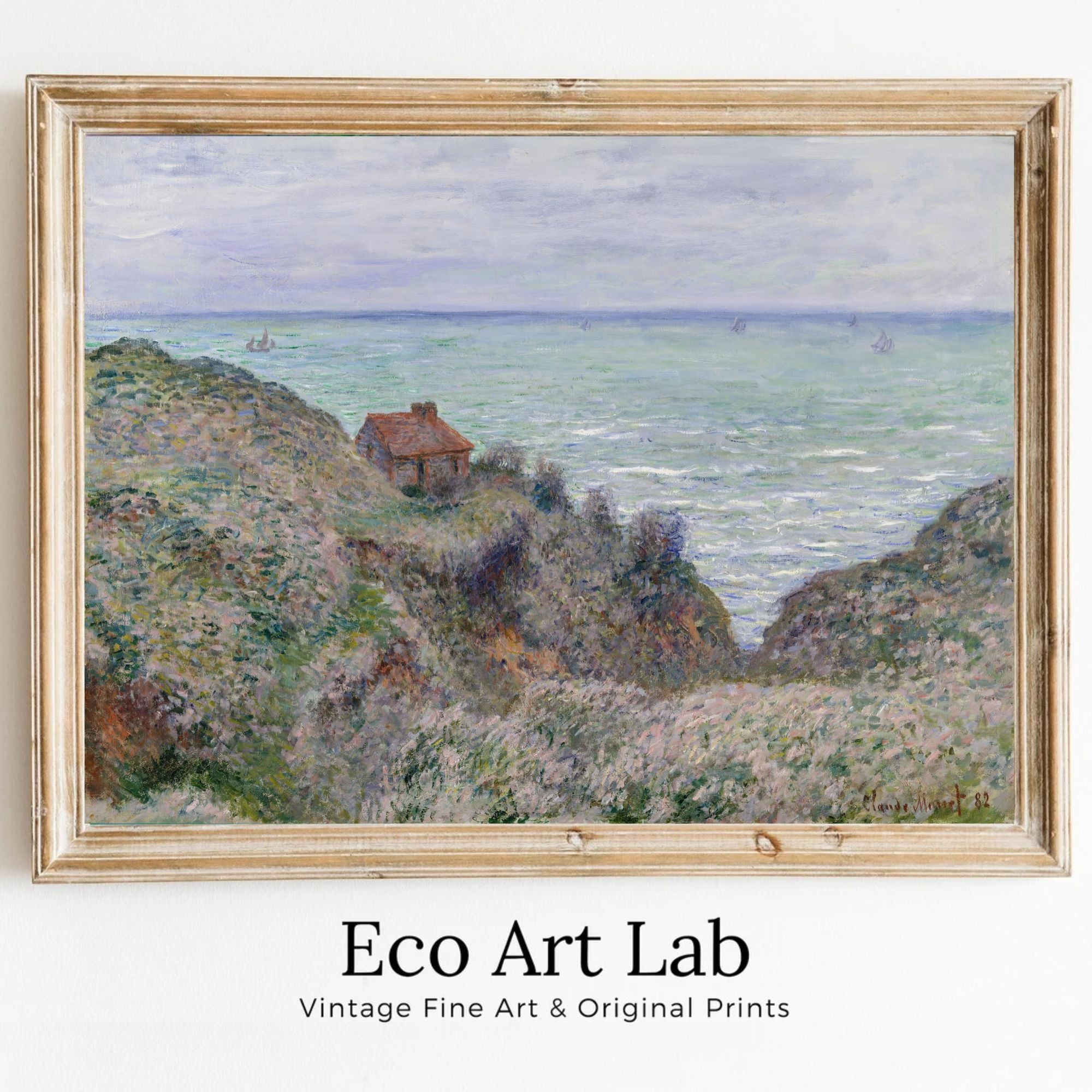A framed impressionist landscape painting of a coastal scene with green and purple hills, a small house, and a pale blue sea under a cloudy sky, shown with the text 'Eco Art Lab Vintage Fine Art & Original Prints' below the frame.